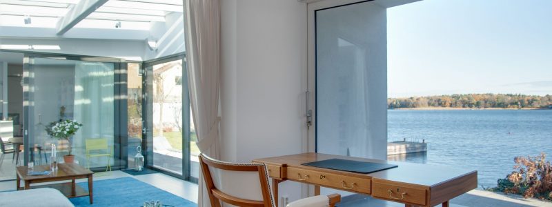 A luxury beach house with glass windows and the beautiful scenery of the sea in the background